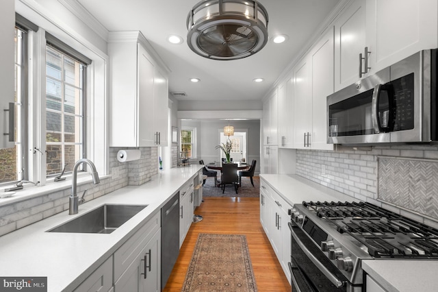 kitchen featuring light wood-style flooring, a sink, white cabinetry, light countertops, and appliances with stainless steel finishes