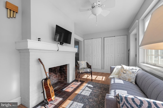 living area featuring dark wood-style floors, a fireplace, baseboards, and ceiling fan