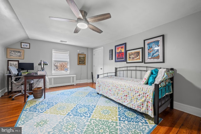 bedroom featuring a ceiling fan, baseboards, radiator heating unit, and wood finished floors