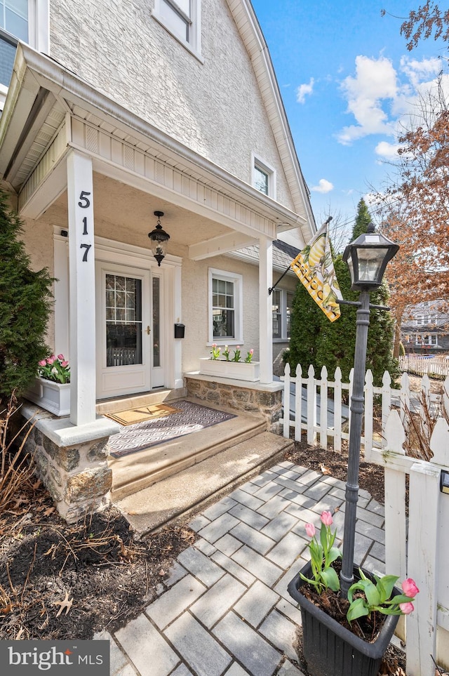 view of exterior entry featuring fence and stucco siding