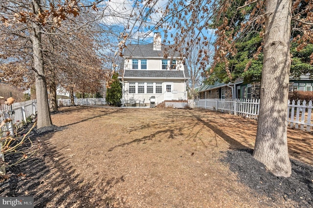 back of property featuring a fenced backyard and a chimney