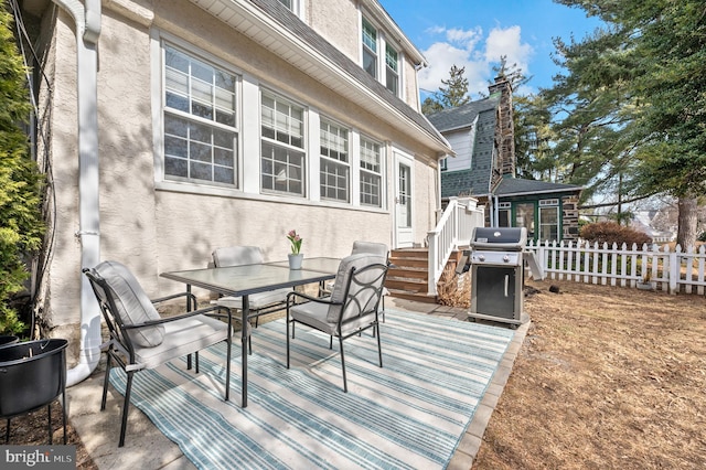 deck with outdoor dining space, fence, and a grill