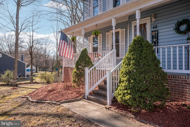 view of exterior entry featuring brick siding and covered porch