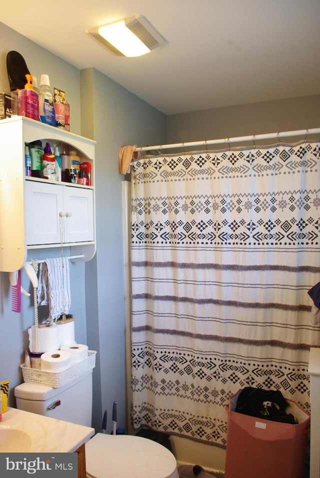 full bath with toilet, vanity, and curtained shower