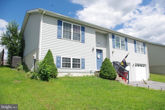 raised ranch with central AC unit, driveway, and a front yard