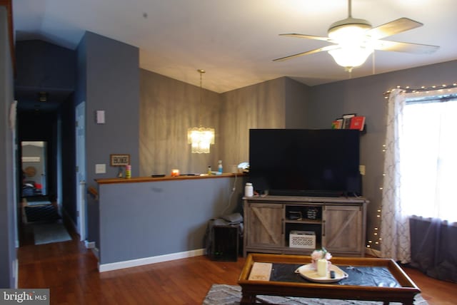 living area with vaulted ceiling, a chandelier, wood finished floors, ceiling fan, and baseboards