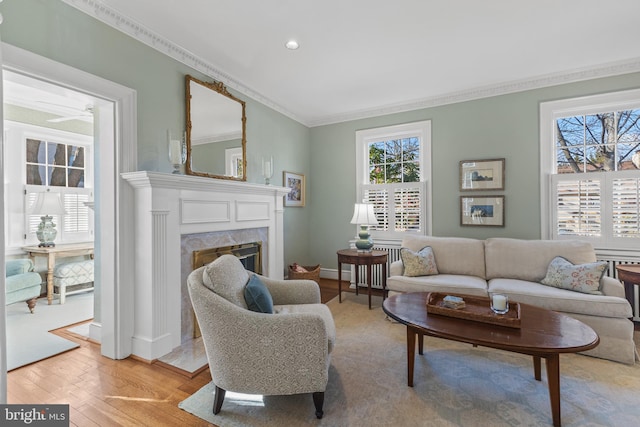 living room with light wood-type flooring, ornamental molding, and a premium fireplace