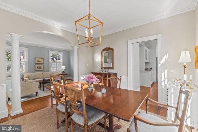 dining space with light hardwood / wood-style flooring, decorative columns, and ornamental molding