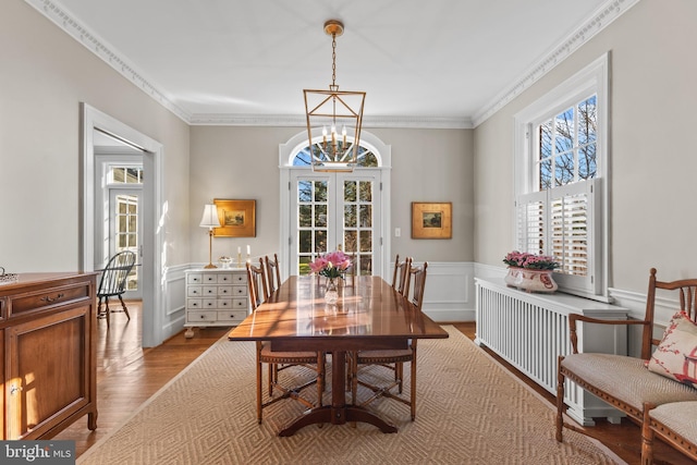 dining area featuring light hardwood / wood-style floors, french doors, crown molding, and a notable chandelier