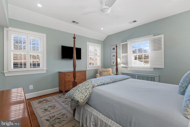 bedroom with radiator, hardwood / wood-style flooring, ceiling fan, and lofted ceiling