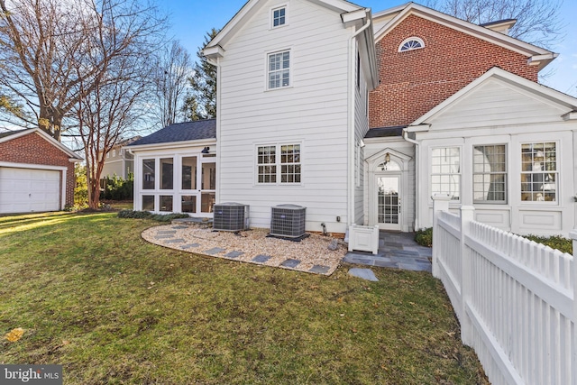 back of house with a lawn, central AC unit, a garage, and a sunroom