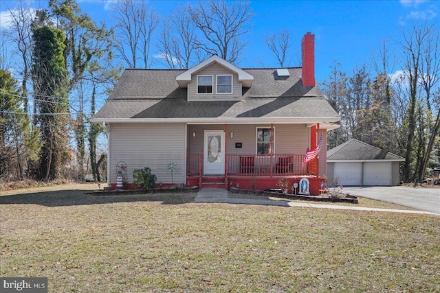 view of front of property featuring covered porch, a front lawn, an outbuilding, and a garage