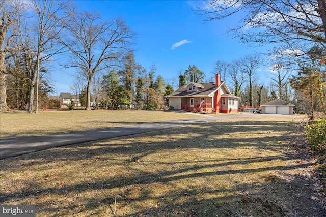 view of property exterior with a garage, a yard, a chimney, and an outbuilding