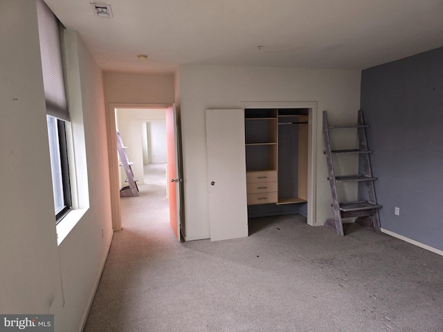 unfurnished bedroom featuring light carpet, a closet, visible vents, and baseboards