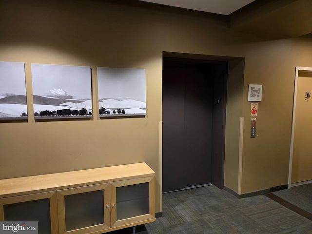 mudroom featuring elevator, baseboards, and dark carpet