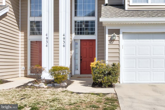 property entrance featuring a garage, driveway, and roof with shingles