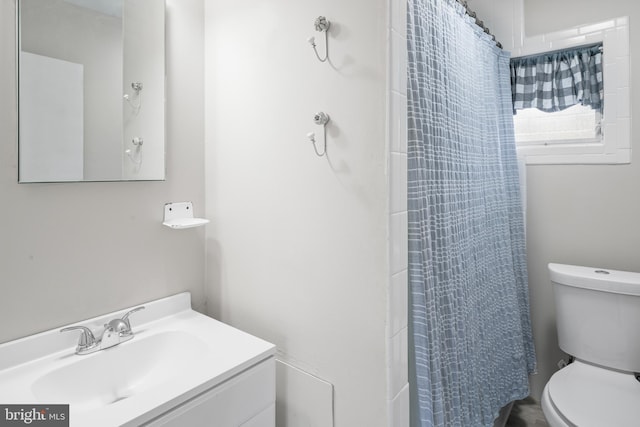 bathroom featuring toilet, curtained shower, and vanity