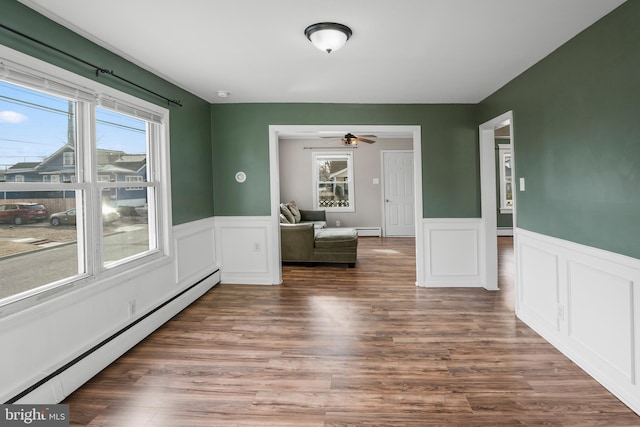 interior space with dark hardwood / wood-style flooring, a baseboard heating unit, and a healthy amount of sunlight