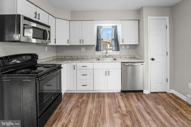 kitchen featuring white cabinetry, dark hardwood / wood-style flooring, sink, light stone counters, and appliances with stainless steel finishes