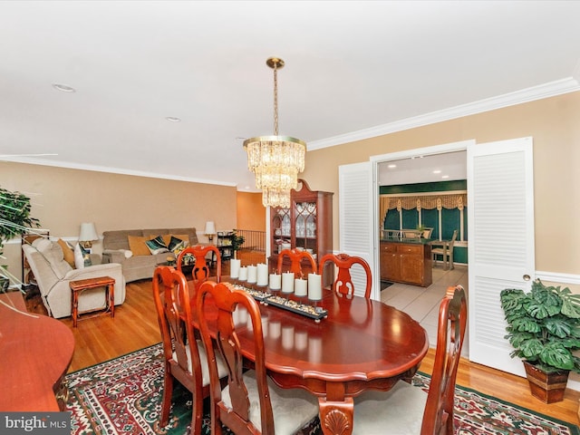 dining room with crown molding, a notable chandelier, and light wood finished floors