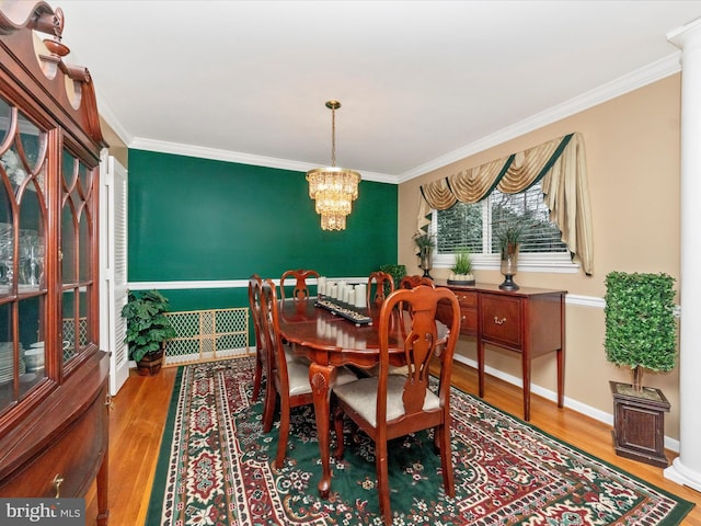 dining area with an inviting chandelier, crown molding, baseboards, and wood finished floors