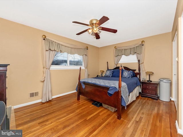 bedroom featuring ceiling fan, wood finished floors, visible vents, and baseboards