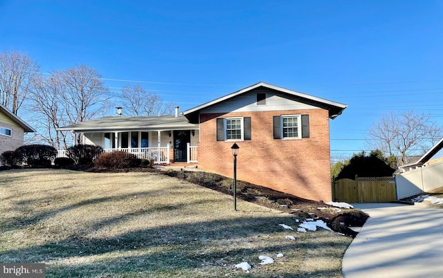 view of front of home with fence, a front lawn, a porch, and brick siding