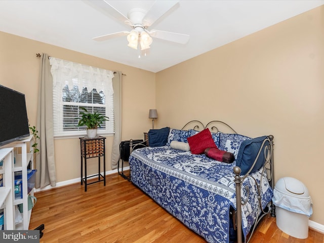 bedroom with a ceiling fan, baseboards, and wood finished floors