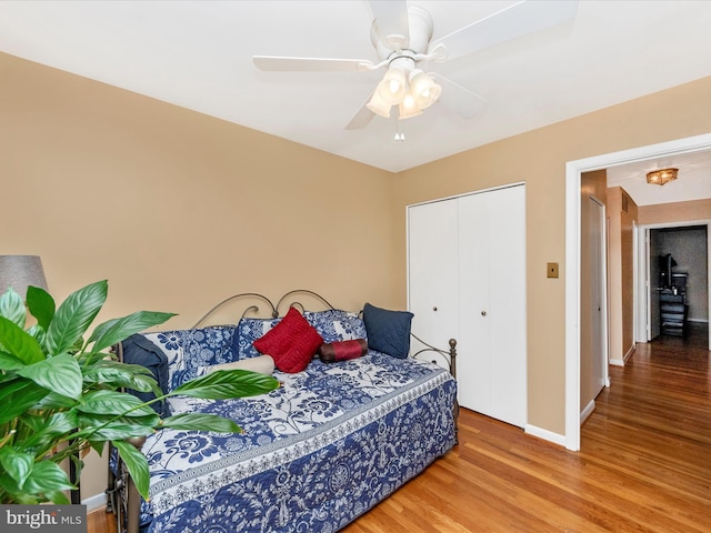 bedroom featuring a closet, wood finished floors, a ceiling fan, and baseboards