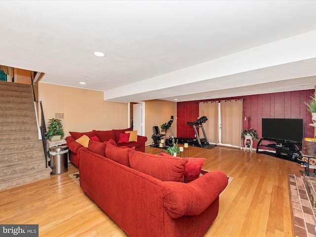 living room featuring wood walls, stairs, wood finished floors, and recessed lighting