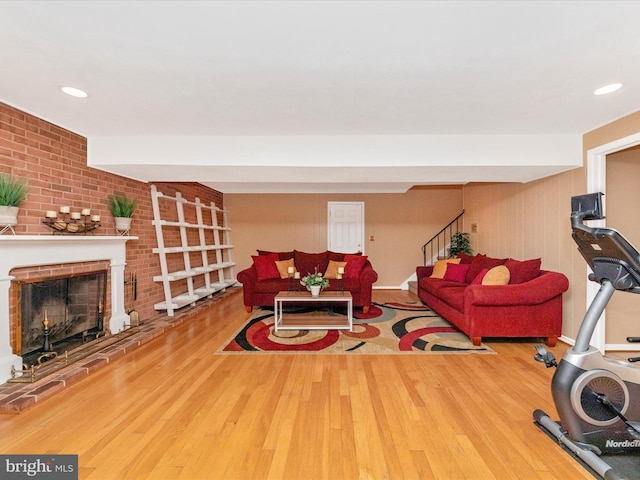 living room featuring stairway, a brick fireplace, wood finished floors, and recessed lighting