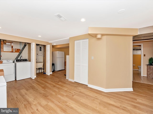 basement with light wood-style flooring, separate washer and dryer, visible vents, baseboards, and freestanding refrigerator