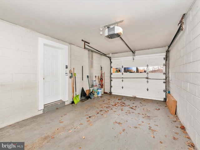 garage featuring concrete block wall and a garage door opener