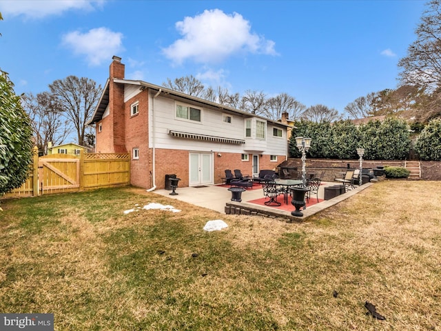 rear view of property featuring a patio, a chimney, a gate, fence, and brick siding