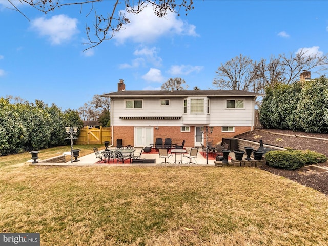 back of property featuring a patio, brick siding, a lawn, and fence