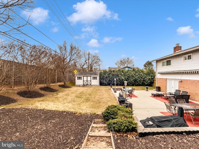 view of yard with an outbuilding, a patio, a storage unit, and a fenced backyard