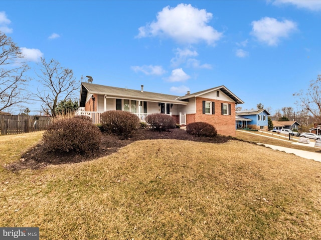 view of front of house featuring a chimney, fence, a front yard, a porch, and brick siding