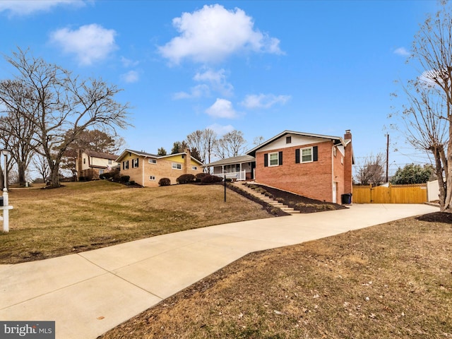 view of property exterior featuring brick siding, a lawn, a chimney, and fence