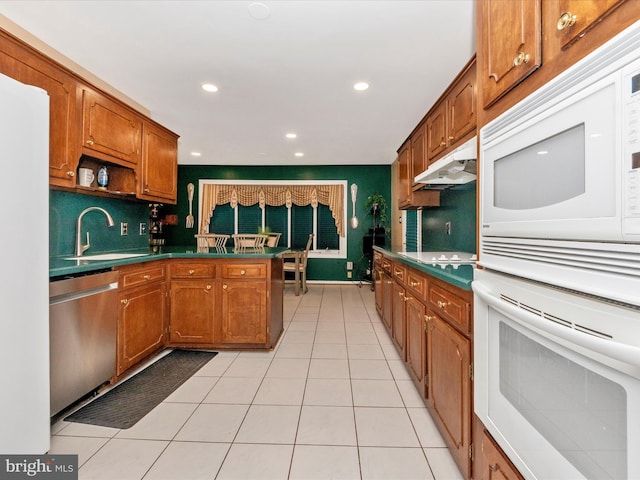 kitchen with white appliances, brown cabinetry, under cabinet range hood, open shelves, and a sink