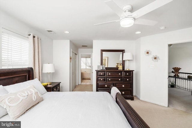 bedroom featuring ensuite bathroom, light colored carpet, and ceiling fan