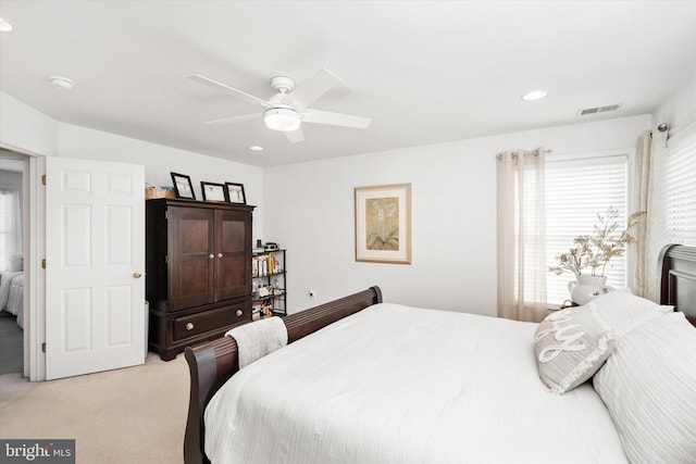 bedroom with ceiling fan, multiple windows, and light colored carpet