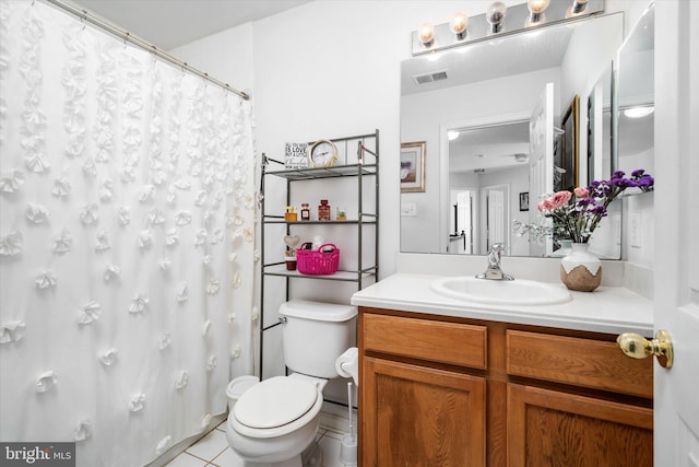 bathroom with toilet, vanity, and tile patterned flooring