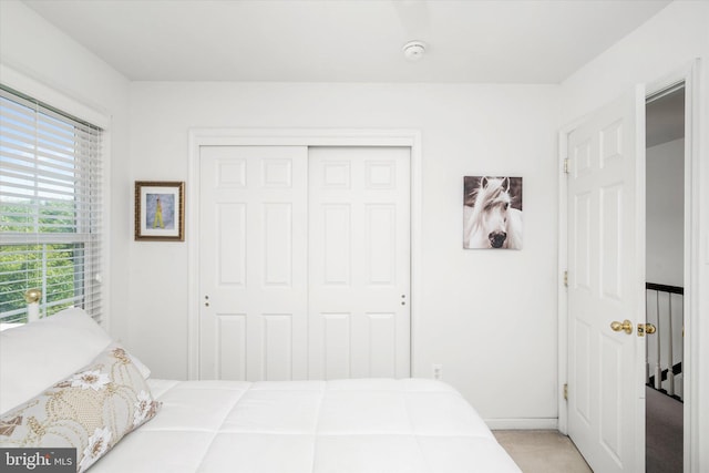 bedroom featuring light carpet and a closet