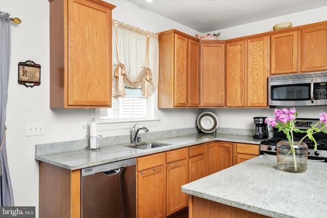 kitchen featuring appliances with stainless steel finishes, sink, and light stone counters