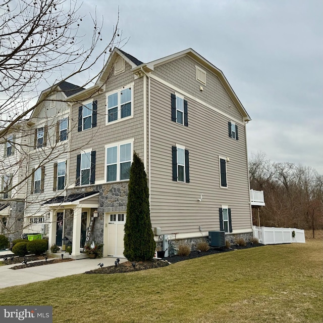 view of home's exterior with cooling unit, a garage, and a lawn