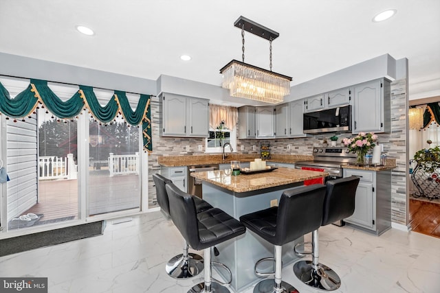 kitchen featuring decorative backsplash, a center island, marble finish floor, stainless steel appliances, and a kitchen bar