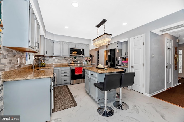 kitchen with stainless steel appliances, visible vents, hanging light fixtures, a kitchen island, and a sink