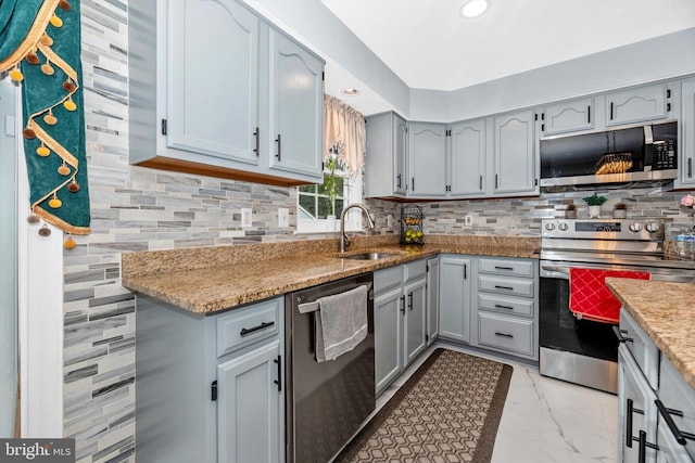 kitchen featuring marble finish floor, appliances with stainless steel finishes, a sink, and tasteful backsplash