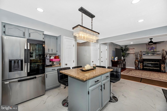 kitchen featuring stainless steel fridge with ice dispenser, open floor plan, a kitchen breakfast bar, a center island, and marble finish floor