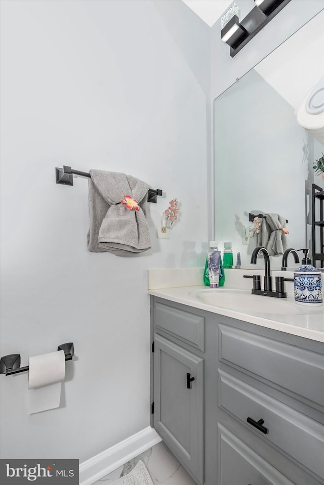 bathroom with marble finish floor, vanity, and baseboards